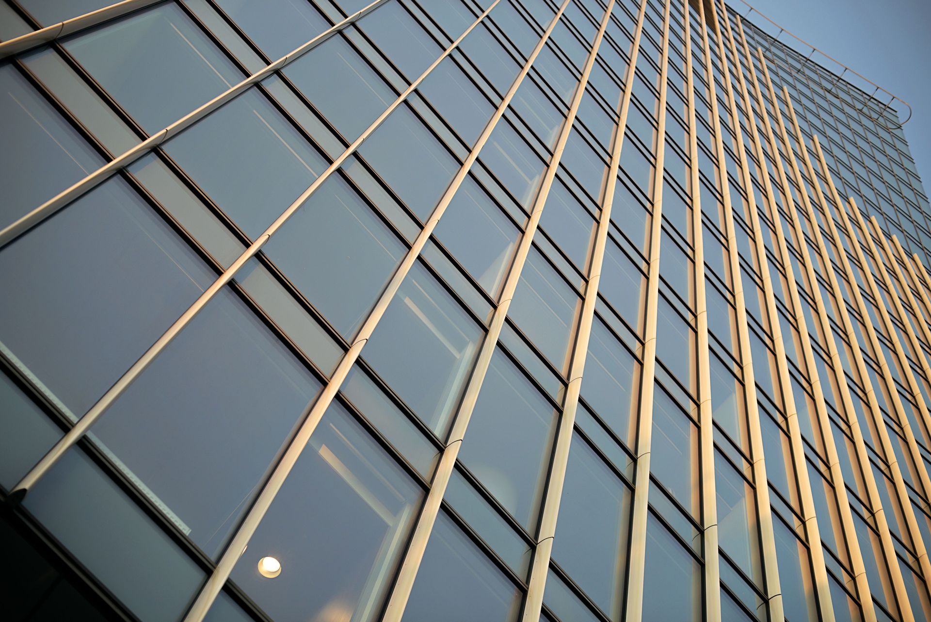 Dynamic perspective of a modern high-rise building with reflective glass panels and geometric patterns.