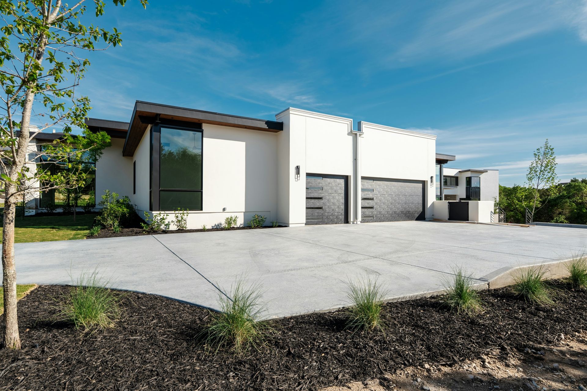 Modern white house, two garage doors, and concrete driveway.