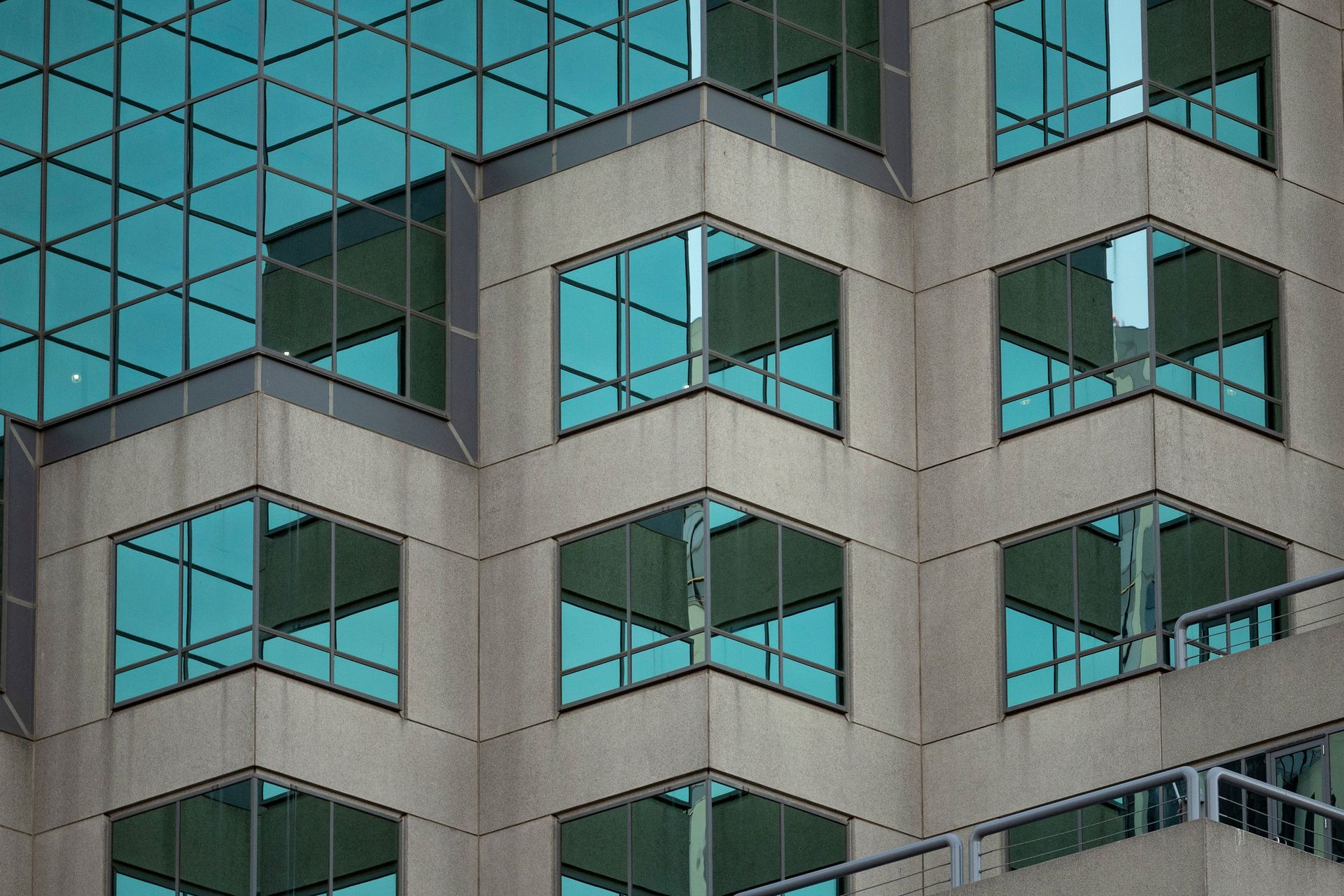 Geometric facade of modern building with reflective glass windows and concrete structure.